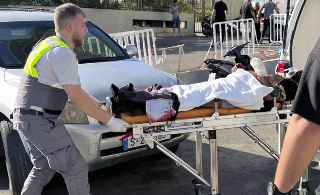 A Civil Defense first-responder carries a wounded man whose handheld pager exploded at al-Zahraa hospital in Beirut, Lebanon, Tuesday, Sept. 17, 2024. (AP Photo/Hussein Malla)