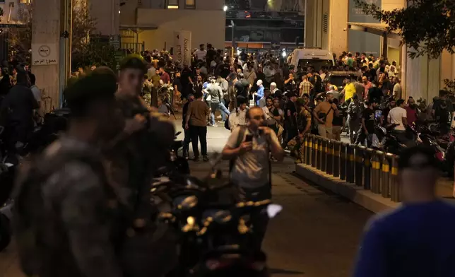 People gather outside the American University hospital after the arrival of several people who were wounded by exploding handheld pagers, in Beirut, Lebanon, Tuesday, Sept. 17, 2024. (AP Photo/Hassan Ammar)