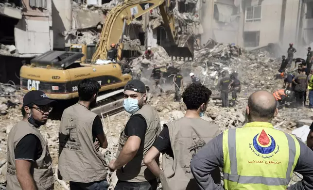 Emergency workers use an excavator to clear the rubble at the site of Friday's Israeli strike in Beirut's southern suburbs, Saturday, Sept. 21, 2024. (AP Photo/Bilal Hussein)