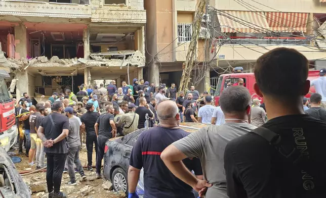 Residents look on as rescuers arrive at the scene of an Israeli missile strike in the southern suburbs of Beirut, Friday, Sept. 20, 2024. (AP Photo/Hassan Ammar)