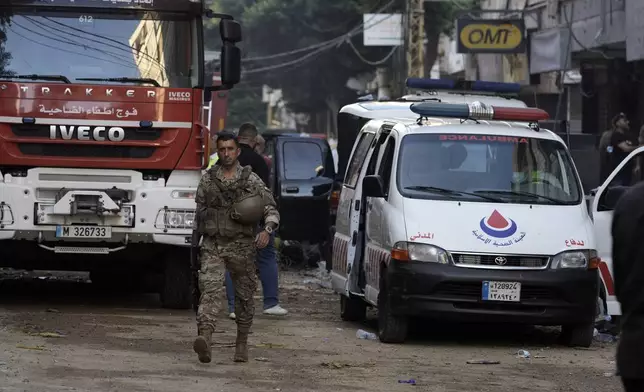 A Lebanese soldier walks near an ambulance an a firefighter truck, securing the area a day after an Israeli missile strike in Beirut's southern suburbs, Saturday, Sept. 21, 2024. (AP Photo/Bilal Hussein)