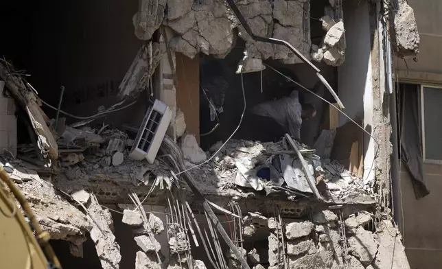 A couple try to salvage some of their belongings from a damaged apartment at the site of Friday's Israeli strike in Beirut's southern suburb, Sunday, Sept. 22, 2024. (AP Photo/Bilal Hussein)