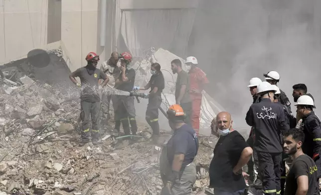 Civil defense workers extinguish a fire as smoke rises from the site of Friday's Israeli strike in Beirut's southern suburbs, Saturday, Sept. 21, 2024. (AP Photo/Bilal Hussein)