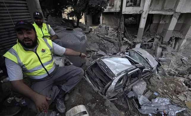 A rescuers gestures near a damaged car at the site of Friday's Israeli strike in Beirut's southern suburbs, Saturday, Sept. 21, 2024. (AP Photo/Bilal Hussein)