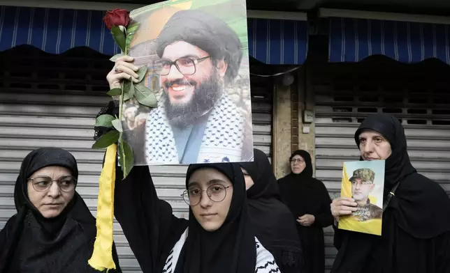 Hezbollah supporters carry pictures of Hezbollah commander Ibrahim Akil, right, and Hezbollah leader Hassan Nasrallah, centre, during Akil's funeral procession in Beirut's southern suburb, Sunday, Sept. 22, 2024. (AP Photo/Bilal Hussein)