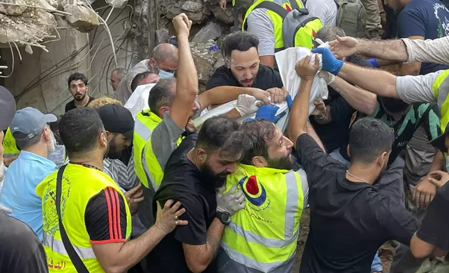 Rescuers carry a body at the scene of a missile strike in the southern suburbs of Beirut, Friday, Sept. 20, 2024. (AP Photo/Bilal Hussein)