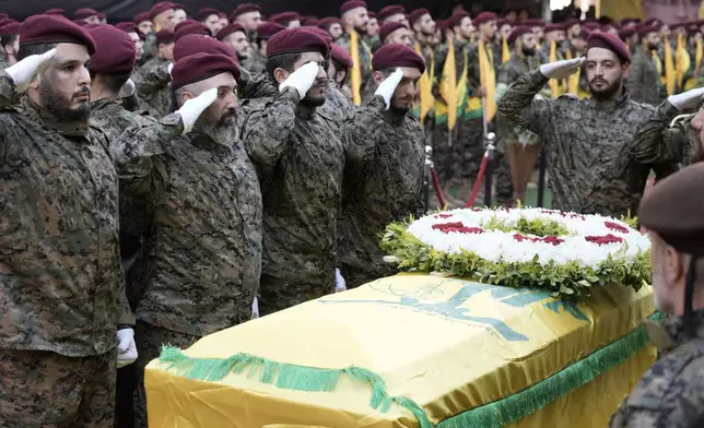 Hezbollah members salute near the coffin of Hezbollah commander Ibrahim Akil during the funeral procession in Beirut's southern suburb, Sunday, Sept. 22, 2024. (AP Photo/Bilal Hussein)