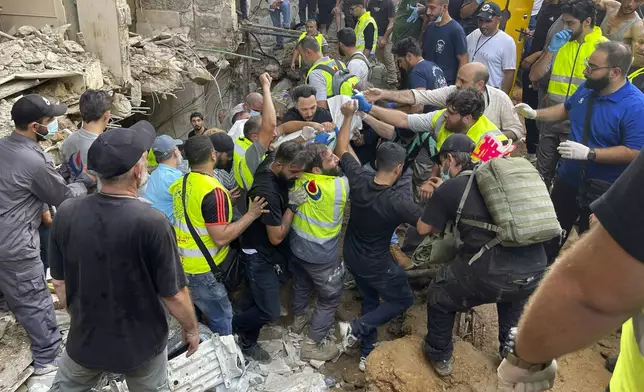 Rescuers carry a body at the scene of a missile strike in the southern suburbs of Beirut, Friday, Sept. 20, 2024. (AP Photo/Bilal Hussein)