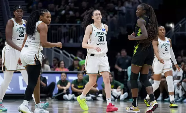 New York Liberty forward Breanna Stewart (30) smiles during the second half of a WNBA basketball game as forward Jonquel Jones (35) and forward Betnijah Laney-Hamilton, second from left, look on against Seattle Storm center Ezi Magbegor, Friday, Aug. 30, 2024, in Seattle. The Liberty won 98-85. (AP Photo/Lindsey Wasson)