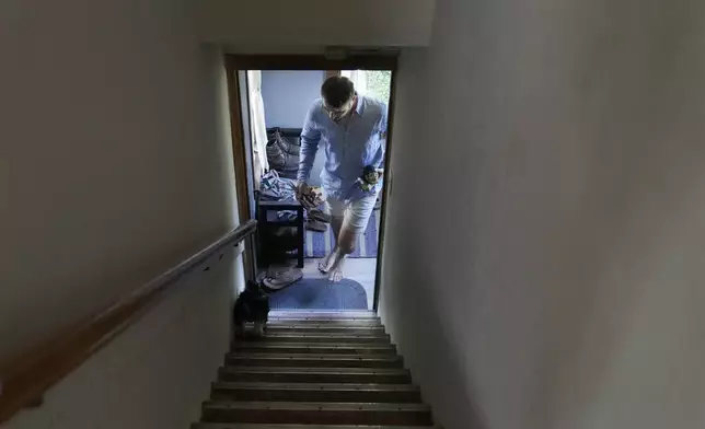 Steven Manetta, a cancer patient, returns from the garden with an eggplant for dinner as his dog Basil leads him up the stairs at his home in Lemont, Ill., Thursday, Aug. 29, 2024. (AP Photo/Charles Rex Arbogast)