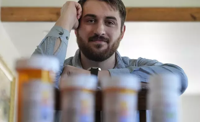 Cancer patient Steven Manetta sits for a portrait Monday, Sept. 9, 2024, in his Lemont, Ill., home with four of the five medicines he takes daily to battle the nausea from his chemotherapy. (AP Photo/Charles Rex Arbogast)