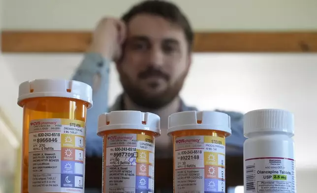 Cancer patient Steven Manetta sits for a portrait Monday, Sept. 9, 2024, in his Lemont, Ill., home with four of the five medicines he takes daily to battle the nausea from his chemotherapy. (AP Photo/Charles Rex Arbogast)