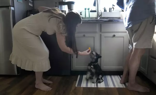 Julia Manetta feeds Basil a piece of watermelon as she and her husband, Steven, prepare dinner Thursday, Aug. 29, 2024, in their Lemont, Ill., home. (AP Photo/Charles Rex Arbogast)