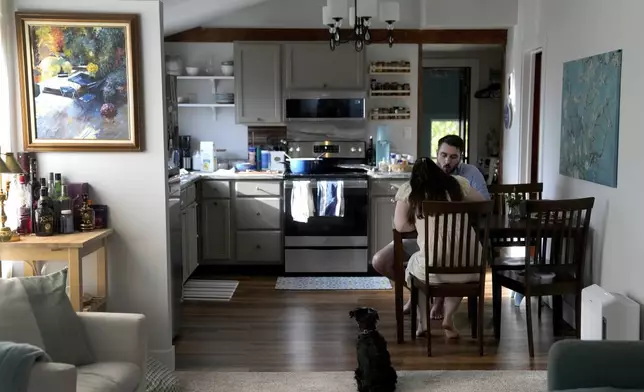 Julia and Steven Manetta eat dinner as their dog, Basil, watches closely Thursday, Aug. 29, 2024, in their Lemont, Ill., home. (AP Photo/Charles Rex Arbogast)