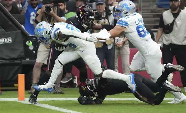 Detroit Lions running back Jahmyr Gibbs (26) scores a touchdown on a run after receiving a lateral from wide receiver Amon-Ra St. Brown during the first half of an NFL football game against the Arizona Cardinals Sunday, Sept. 22, 2024, in Glendale, Ariz. (AP Photo/Rick Scuteri)