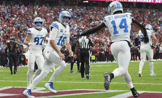 Detroit Lions wide receiver Amon-Ra St. Brown (14) celebrates his five-yard touchdown reception with quarterback Jared Goff (16) during the first half of an NFL football game against the Arizona Cardinals Sunday, Sept. 22, 2024, in Glendale, Ariz. (AP Photo/Rick Scuteri)