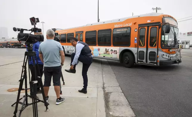 A bus passes by waiting news media in front of a Los Angeles MTA bus depot near the site where overnight a bus was hijacked by an armed subject with passengers on board Wednesday, Sept. 25, 2024, in Los Angeles. One person was fatally shot before police apprehended the suspect. (AP Photo/Ryan Sun)