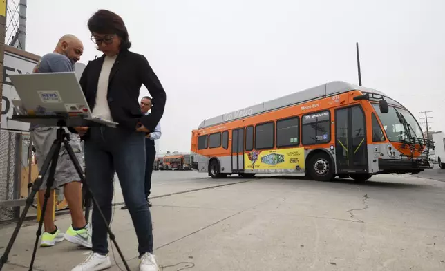 A bus passes by news media in front of a Los Angeles MTA bus depot near the site where an overnight a bus was hijacked by an armed suspect with passengers on board Wednesday, Sept. 25, 2024, in Los Angeles. (AP Photo/Ryan Sun)