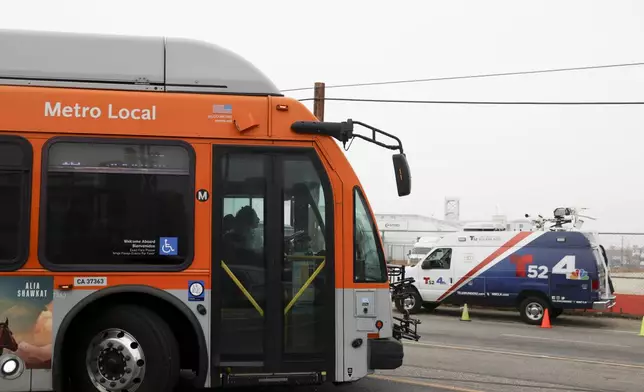 A bus passes by a news van in front of a Los Angeles MTA bus depot near the site where overnight a bus was hijacked by an armed subject with passengers on board Wednesday, Sept. 25, 2024, in Los Angeles. (AP Photo/Ryan Sun)