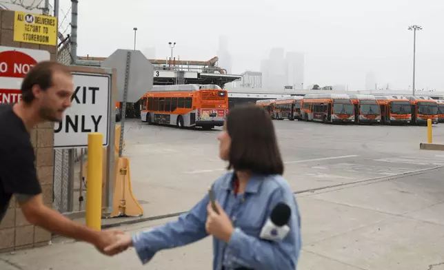 News media prepare to go live in front of a Los Angeles MTA bus depot near the site where overnight a bus was hijacked by an armed subject with passengers on board Wednesday, Sept. 25, 2024, in Los Angeles. One person was fatally shot before police apprehended the suspect. (AP Photo/Ryan Sun)