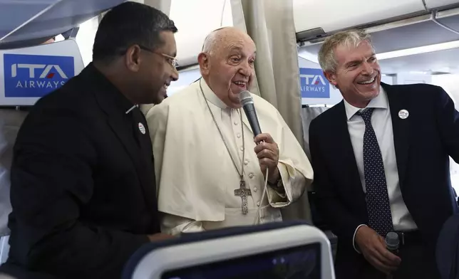 Pope Francis, center, speaks to the media aboard his flight bound for Luxembourg, where he will start a four-day apostolic journey in Luxembourg and Belgium, Thursday, Sept. 26, 2024. (Guglielmo Mangiapane/Pool Photo via AP)