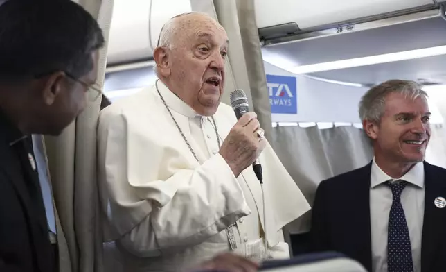 Pope Francis, center, speaks to the media aboard his flight bound for Luxembourg, where he will start a four-day apostolic journey in Luxembourg and Belgium, Thursday, Sept. 26, 2024. (Guglielmo Mangiapane/Pool Photo via AP)