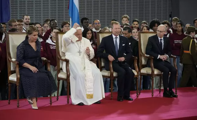 Pope Francis flanked by Grand Duchess Maria Teresa, left, Luxembourg's Grand Duke Henri, second form right, and by the Prime Minister Luc Friede attends the welcome ceremony upon his arrival at Findel International Airport in Luxembourg, Thursday, Sept. 26, 2024. (AP Photo/Andrew Medichini)