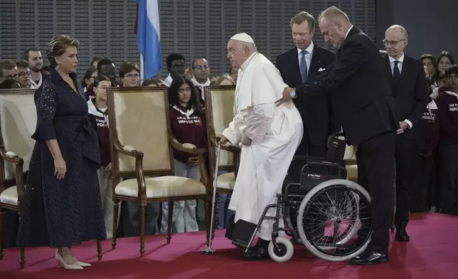 Pope Francis flanked by Grand Duchess Maria Teresa, left, Luxembourg's Grand Duke Henri, second form right, and by the Prime Minister Luc Friede attends the welcome ceremony upon his arrival at Findel International Airport in Luxembourg, Thursday, Sept. 26, 2024. (AP Photo/Andrew Medichini)