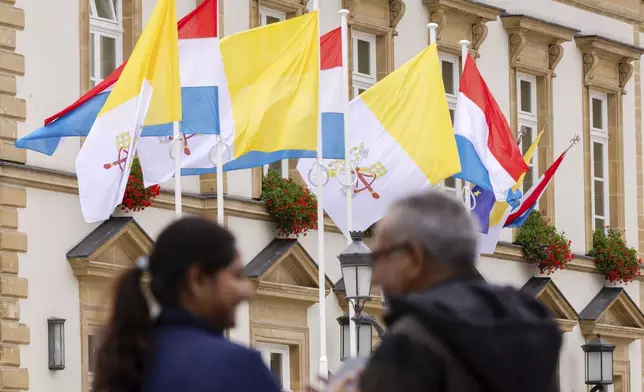 Flags of Vatican City and Luxembourg wave outside the Luxembourg City Hall a day before for the trip of Pope Francis to Luxembourg and Belgium, Wednesday, Sept. 25, 2024, (AP Photo/Geert Vanden Wijngaert)