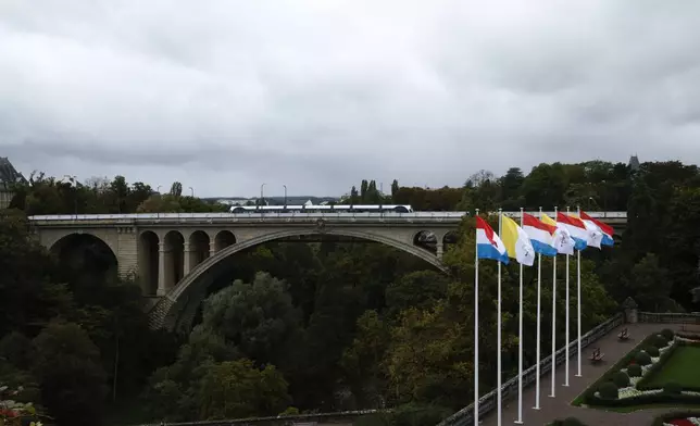 A tramway crosses the iconic Adolphe Bridge where flags of the Vatican and Luxembourg are seen waving in the surrounding gardens on the day before Pope Francis' trip to Luxembourg and Belgium, Wednesday, Sept. 25, 2024, (AP Photo/Omar Havana)