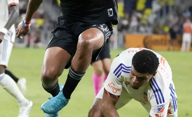 Nashville SC midfielder Anibal Godoy, left, leaps over FC Cincinnati defender Miles Robinson, right, as they chase the ball during the second half of an MLS soccer match Saturday, Sept. 21, 2024, in Nashville, Tenn. (AP Photo/George Walker IV)