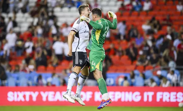 D.C. United goalkeeper Alex Bono, right, and defender Lucas Bartlett, left, celebrate after midfielder Gabriel Pirani scored during second-half MLS soccer match action against Toronto FC in Toronto, Saturday, Aug. 31, 2024. (Christopher Katsarov/The Canadian Press via AP)