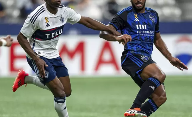 Vancouver Whitecaps' Sam Adekugbe, left, and San Jose Earthquakes' Carlos Akapo, right, vie for the ball during the first half of an MLS soccer match in Vancouver, British Columbia, Saturday, Sept. 14, 2024. (Ethan Cairns/The Canadian Press via AP)