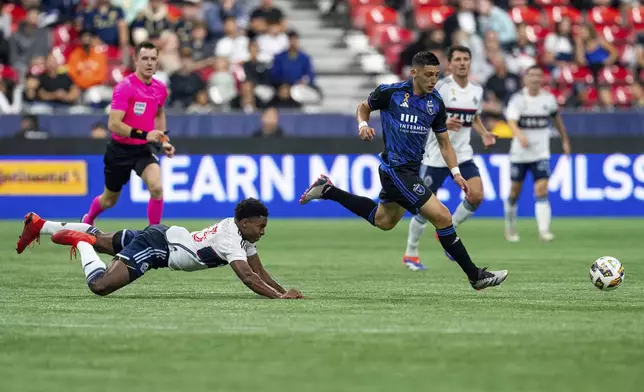 Vancouver Whitecaps' Ralph Priso, front left, falls as San Jose Earthquakes' Cristian Espinoza, front right, vies for the ball during the first half of an MLS soccer match in Vancouver, British Columbia, Saturday, Sept. 14, 2024. (Ethan Cairns/The Canadian Press via AP)