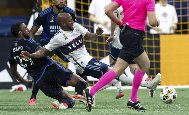 San Jose Earthquakes' Carlos Akapo, left, slide-tackles Vancouver Whitecaps' Fafa Picault, center, during the first half of an MLS soccer match in Vancouver, British Columbia, Saturday, Sept. 14, 2024. (Ethan Cairns/The Canadian Press via AP)