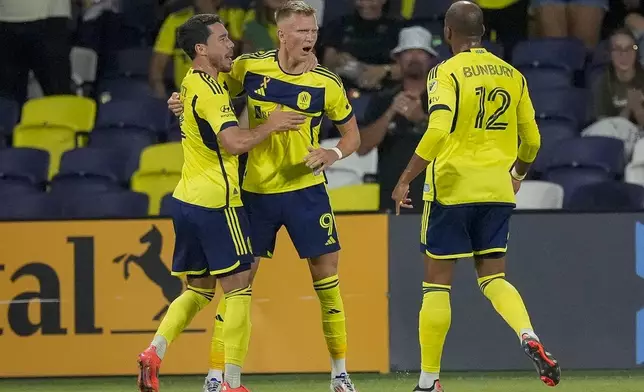 Nashville SC forward Sam Surridge (9) celebrates a goal with defender Daniel Lovitz, left, and forward Teal Bunbury (12) during the first half of an MLS soccer match against the Chicago Fire, Wednesday, Sept. 18, 2024, in Nashville, Tenn. (AP Photo/George Walker IV)