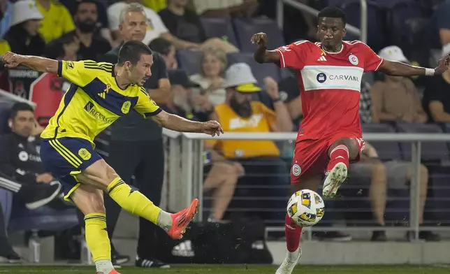 Chicago Fire midfielder Maren Haile-Selassie, right, blocks a kick by Nashville SC defender Daniel Lovitz, left, during the first half of an MLS soccer match Wednesday, Sept. 18, 2024, in Nashville, Tenn. (AP Photo/George Walker IV)