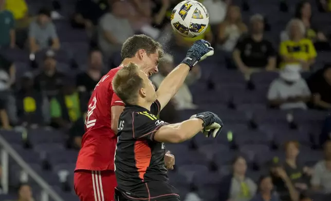 Nashville SC goalkeeper Joe Willis, front, punches the ball away from Chicago Fire forward Tom Barlow, right, during the first half of an MLS soccer match Wednesday, Sept. 18, 2024, in Nashville, Tenn. (AP Photo/George Walker IV)