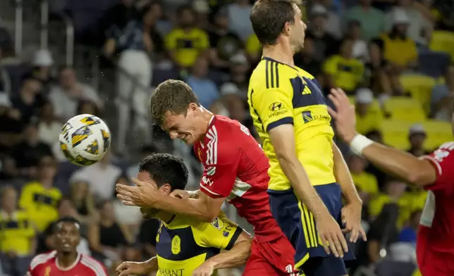 Chicago Fire forward Tom Barlow, center, heads the ball past Nashville SC defender Daniel Lovitz, left, and Nashville SC defender Jack Maher, right, during the first half of an MLS soccer match Wednesday, Sept. 18, 2024, in Nashville, Tenn. (AP Photo/George Walker IV)