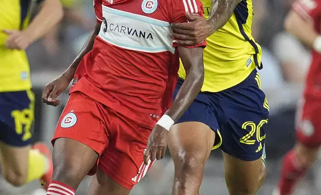 Nashville SC midfielder Anibal Godoy (20) grabs Chicago Fire midfielder Maren Haile-Selassie, left, as they chase the ball during the first half of an MLS soccer match Wednesday, Sept. 18, 2024, in Nashville, Tenn. (AP Photo/George Walker IV)