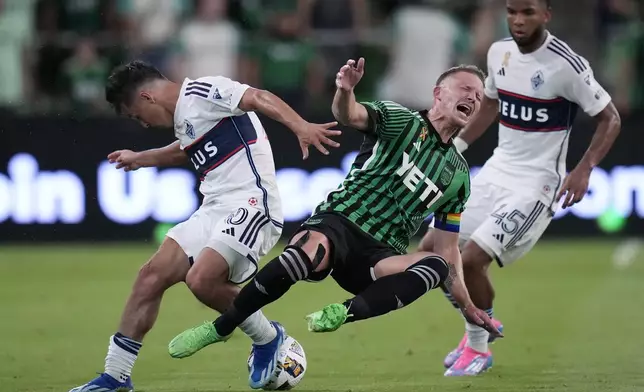 Austin FC midfielder Alexander Ring, center, is tripped as he and Vancouver Whitecaps midfielder Andres Cubas, left, compete for the ball during the first half of an MLS soccer match in Austin, Texas, Saturday, Aug. 31, 2024. (AP Photo/Eric Gay)