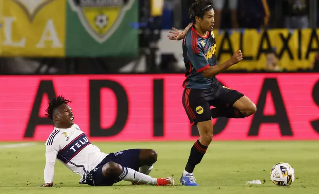 Los Angeles Galaxy's Miki Yamane, right, dribbles past Vancouver Whitecaps' Edier Ocampo during the first half of an MLS soccer match Saturday, Sept. 21, 2024, in Carson, Calif. (AP Photo/Etienne Laurent)