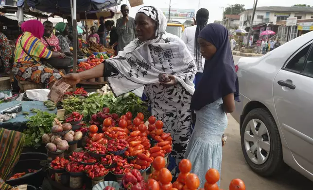 Idowu Bello, 56, buys onions to prepare a pot of soup at a market in Ibadan, Nigeria, Friday, Sept. 13, 2024. (AP Photo/Sunday Alamba)