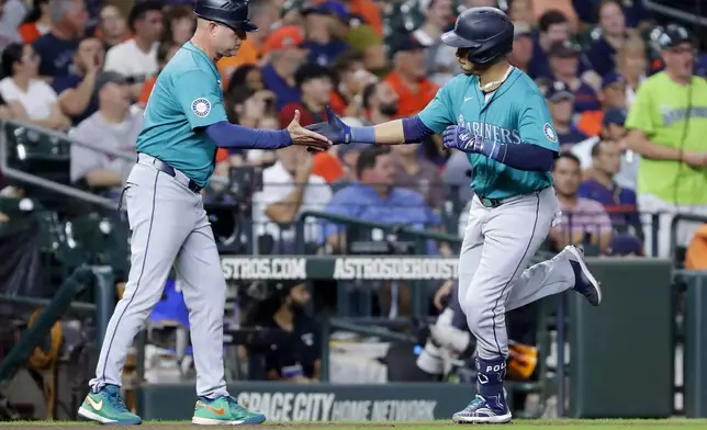 Seattle Mariners' Jorge Polanco is greet by third base coach Manny Acta, left, after hitting a home run against the Houston Astros during the second inning of a baseball game Tuesday, Sept. 24, 2024, in Houston. (AP Photo/Michael Wyke)