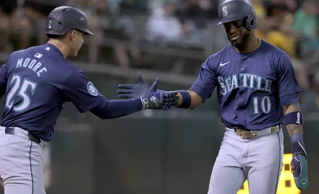 Seattle Mariners outfielder Victor Robles (10) is congratulated by Dylan Moore (25) after scoring on a single by Mitch Garver during the fourth inning of a baseball game against the Oakland Athletics in Oakland, Calif., Wednesday, Sept. 4, 2024. (AP Photo/Jed Jacobsohn)