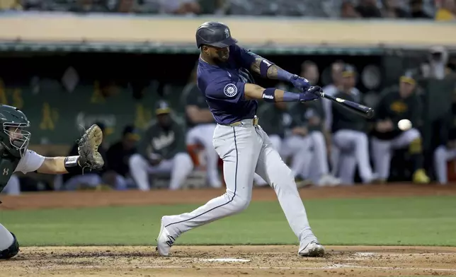 Seattle Mariners outfielder Victor Robles, right, hits a double in front of Oakland Athletics catcher Shea Langeliers during the fourth inning of a baseball game in Oakland, Calif., Wednesday, Sept. 4, 2024. (AP Photo/Jed Jacobsohn)