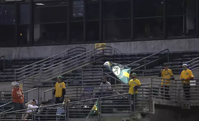 Fans stand in the bleachers during the fifth inning of a baseball game between the Oakland Athletics and the Seattle Mariners in Oakland, Calif., Wednesday, Sept. 4, 2024. (AP Photo/Jed Jacobsohn)