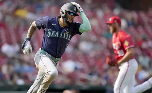 Seattle Mariners' J.P. Crawford, left, rounds first on his way to an RBI double off St. Louis Cardinals pitcher Chris Roycroft, right, during the ninth inning of a baseball game Sunday, Sept. 8, 2024, in St. Louis. (AP Photo/Jeff Roberson)