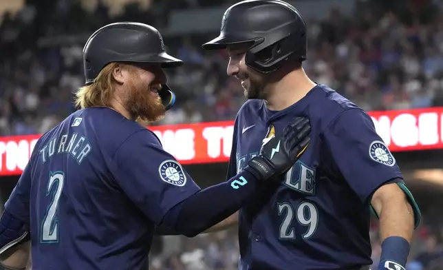 Seattle Mariners' Cal Raleigh (29) celebrates after his home run with teammate Justin Turner (2) during the third inning of a baseball game against the Texas Rangers, Sunday, Sept. 22, 2024, in Arlington, Texas. (AP Photo/LM Otero)