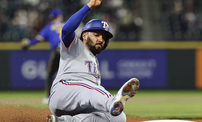 Texas Rangers' Marcus Semien reaches third base after tagging from second on a sacrifice fly by Adolis Garcia in the first inning of a baseball game against the Seattle Mariners, Friday, Sept. 13, 2024, in Seattle. (Dean Rutz/The Seattle Times via AP)